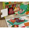 A close-up view of an open advent calendar with a Christmas theme. Inside one of the doors, a small bear figurine is visible. The scene depicts a cozy winter setting with a fireplace, stockings, a chair, and other animal figurines. Anteprima dell’immagine prodotto