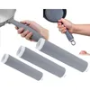 Hands holding cookware handles with silicone grips, and three silicone sleeves laid out. Anteprima dell’immagine prodotto