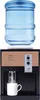 A freestanding desktop water dispenser with a water bottle on top, dispensing water into a mug. Náhled obrázku produktu