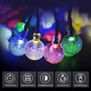 Close-up of four illuminated glass ball-shaped lights on a string, with a dark, bokeh background of other colored lights. Below the lights are five icons with German text describing features. Produktbild-Vorschau