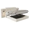 A beige upholstered bed frame with the mattress lifted to reveal storage space underneath. Two small reading lamps are attached to the headboard. Produktbild-Vorschau