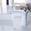 A white faucet is shown in a bathroom setting, with a sink filled with water. Náhled obrázku produktu
