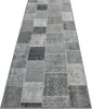 A long, rectangular rug with a patchwork design in various shades of gray and anthracite, laid out on a white background. Produktbild-Vorschau