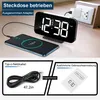 A digital alarm clock is shown plugged into a wall socket and charging a smartphone wirelessly. The image is divided into sections showing the clock, a charging cable, and an instruction manual. Produktbild-Vorschau