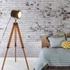 A vintage-style tripod floor lamp is positioned next to a bed with striped bedding and decorative pillows. Anteprima dell’immagine prodotto