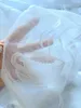 A hand holding a sheer white curtain with a coffee cup pattern. Produktbild-Vorschau