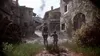 Two people walking down a cobblestone street in a medieval village. Produktbild-Vorschau