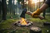 A hand holding an axe over a campfire in a forest. Anteprima dell’immagine prodotto