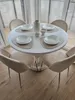 A round dining table with four chairs set up for a meal. Produktbild-Vorschau