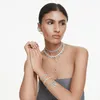 A woman wearing multiple pieces of Swarovski jewelry, including necklaces and bracelets. Produktbild-Vorschau
