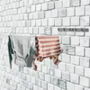 A retractable clothesline mounted on a tiled wall with clothes hanging on it. Voir les images du produit