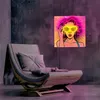 A pop art style LED neon art piece featuring a woman with sunglasses is displayed on a concrete wall above a modern lounge chair. Voir les images du produit