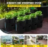 A hydroponic system with multiple buckets and plants, set against a backdrop of a patio and garden. Anteprima dell’immagine prodotto