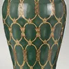 A close-up view of a green vase with a gold and brown patterned design. Podgląd zdjęcia produktu