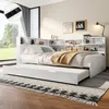 A white daybed with a pull-out trundle bed, set up in a bedroom with a large window and decorative artwork on the wall. Produktbild-Vorschau