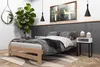 A bedroom scene with a wooden bed frame, bedding, a plant, and decorative items. Produktbild-Vorschau