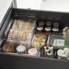 An open kitchen drawer filled with various food storage containers and items. Produktbild-Vorschau
