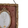 A close-up view of a decorative picture frame with an oval opening, showcasing a floral illustration inside. Voir les images du produit