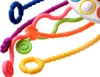 A close-up view of several colorful, flexible teething toys with different textures and shapes, attached to a white object. Náhľad obrázku produktu