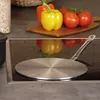 A metal induction pad sits on a stovetop, with vegetables in the background. Produktbild-Vorschau