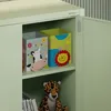 The inside of a light green cabinet with storage boxes and a stuffed toy. Náhľad obrázku produktu