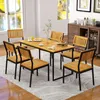 A dining set with a wooden table and chairs is arranged on a rug in a room with natural light coming from windows. Produktbild-Vorschau