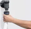 A hand is shown connecting a white ribbed hose to a gray filter pump component attached to a white surface. Produktbild-Vorschau