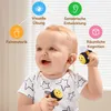 A baby is holding two plush bee toys, with icons and text indicating developmental benefits. Produktbild-Vorschau