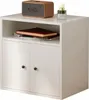 A white storage unit with two doors and an open shelf, featuring a speaker and a bottle on top, and books on the shelf. Produktbild-Vorschau