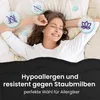 A woman is sleeping comfortably in bed, covered by a black blanket. Icons representing hypoallergenic and dust mite resistance are visible. Produktbild-Vorschau