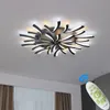 A modern LED ceiling light fixture with a unique, abstract design, mounted on a white ceiling. A remote control is shown in the lower right corner, indicating smart features. Produktbild-Vorschau