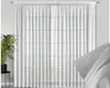 A white sheer curtain with a grid pattern is shown hanging in front of a window. A potted plant is visible to the left. Produktbild-Vorschau
