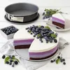 A layered cake with berries and lavender, next to a springform pan and a bowl of berries. Produktbild-Vorschau