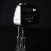 A black hand mixer with silver accents is shown against a black background. Produktbild-Vorschau