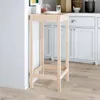 A wooden bar table is placed in a kitchen setting next to white cabinets. Anteprima dell’immagine prodotto