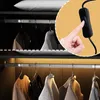 A close-up of a hand pressing a switch for a closet light, with clothes hanging in the closet visible in the background. Produktbild-Vorschau