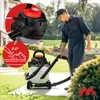 A man is using a wet/dry vacuum cleaner to clean leaves from a paved area in a garden. Produktbild-Vorschau