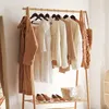 A clothing rack with various garments and shoes, a basket, and a mirror in the background. Produktbild-Vorschau