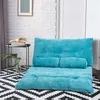 A blue floor sofa is shown in a room with a white brick wall and a black and white patterned rug. Voir les images du produit