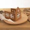 A gingerbread house being decorated with white icing on a wooden board. Voir les images du produit