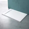 A white shower tray with a linear drain is placed on a concrete floor in front of a teal wall. Produktbild-Vorschau