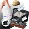 A hand holding a white humidifier, a suitcase packed with clothes, a hat, and an airplane ticket. Produktbild-Vorschau