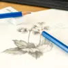 A close-up view of pencils and an eraser on a sketchpad with a drawing of flowers. Podgląd zdjęcia produktu
