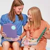 Two young girls are sitting and holding open lunchboxes, showing the contents. Náhľad obrázku produktu