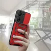 A hand holding a red and black phone case with a ring holder, with a blurred indoor background. Produktbild-Vorschau