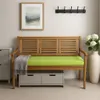 A wooden bench with a green cushion and storage drawers underneath, placed in a room with a framed picture and a vase of flowers. Anteprima dell’immagine prodotto