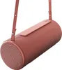 A coral red Bluetooth speaker with a pink strap is hanging against a white background. Produktbild-Vorschau