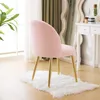 A pink plush chair with gold legs sits on a white fluffy rug in front of a window and a mirror. Podgląd zdjęcia produktu