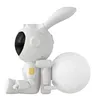 A white robot with rabbit ears sitting next to a textured sphere, likely representing the moon. Náhled obrázku produktu