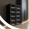 A stack of black shoe boxes with shoes inside, placed in a room with a dark gray wall and a light gray closet. Podgląd zdjęcia produktu